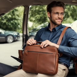 a-man-sits-in-his-car-with-a-brown-laptop-bag-next-to-him--490106622